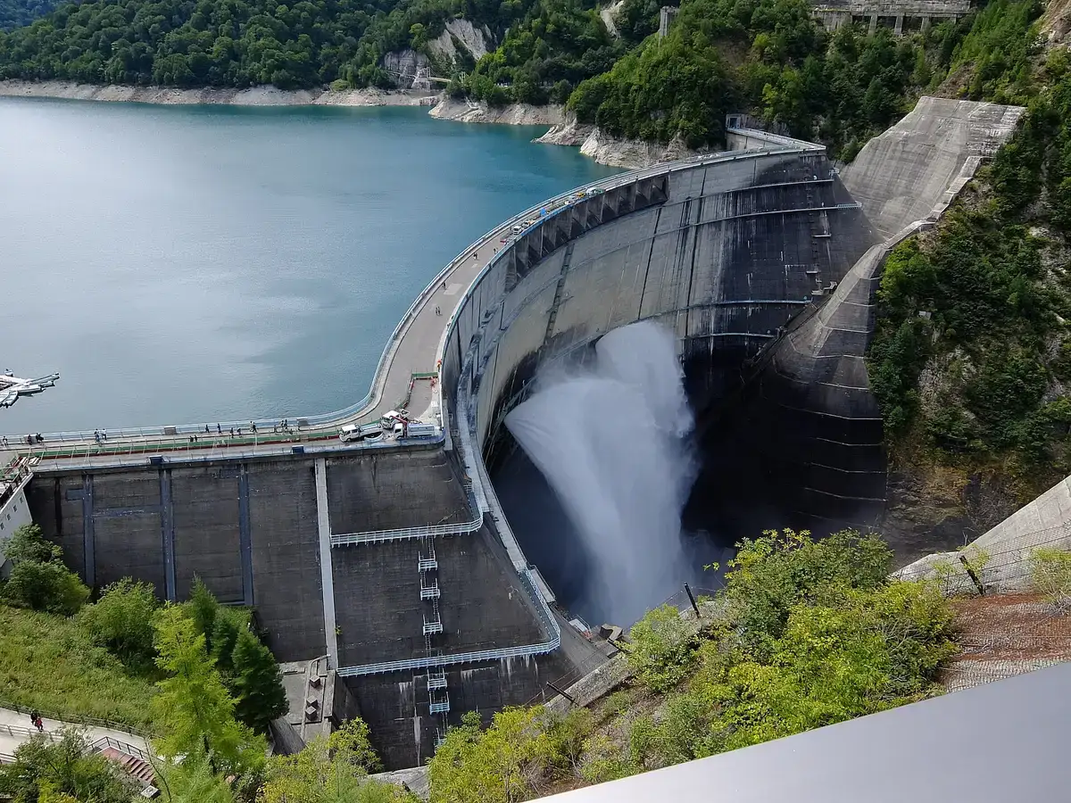 Curving Kurobe Dam wall releasing water beside the reservoir