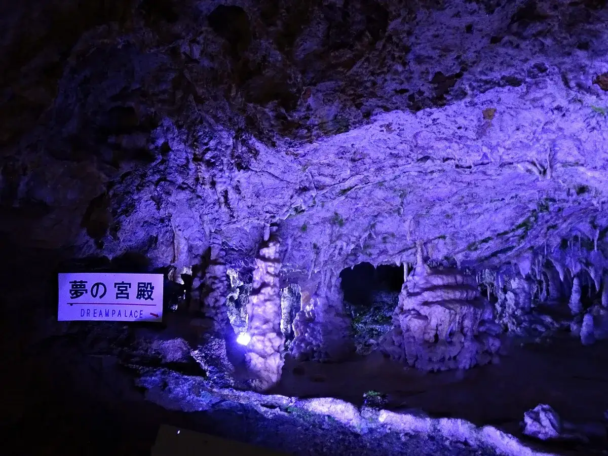 Purple-lit formations around the Dream Palace sign inside Hida Great Limestone Cave