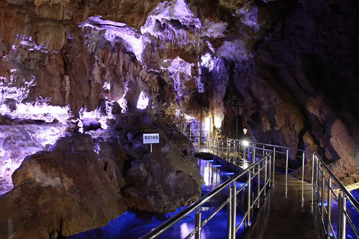Illuminated formations and a railed walkway inside Hida Great Limestone Cave