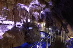 Illuminated formations and a railed walkway inside Hida Great Limestone Cave