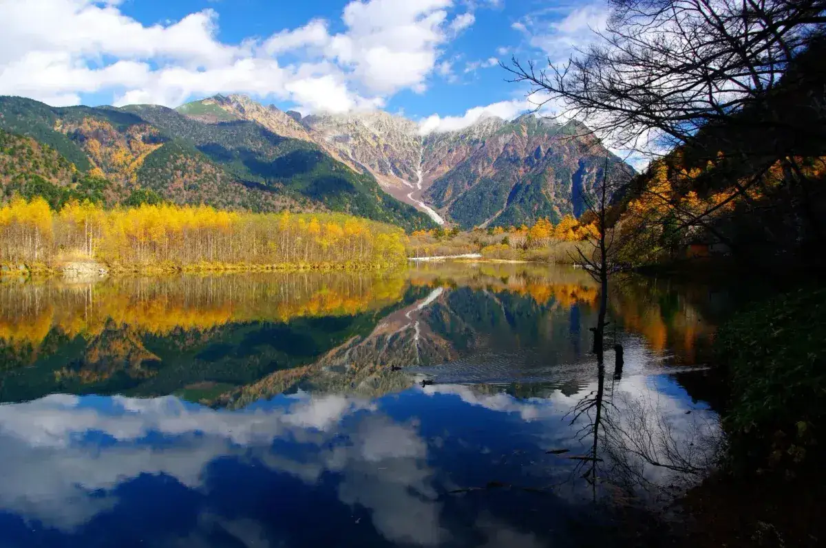 Mountains and yellow autumn trees reflected in a pond