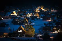 Illuminated gassho-style houses in snow at Shirakawa-go after dusk